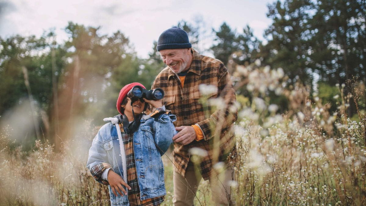Happy little multiracial boy exploring autumn nature with his senior grandfather. Syndromic testing, nature, grandfather, grandson, child, boy, older man.